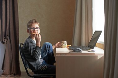 Dizüstü bilgisayar ile oturup mutlu çocuk