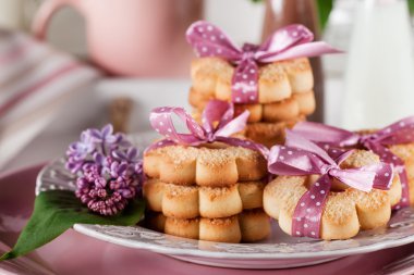 Cookies with pink ribbons on a white plate and chocolate milksha