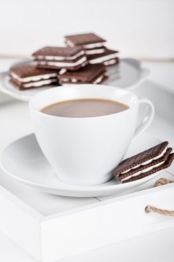 Cup of coffee and plate with cookies on a white tray