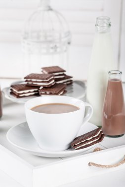 Cup of coffee on a white tray with cookies and chocolate milksha