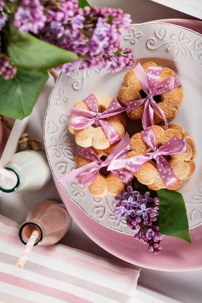 Butter cookies with pink ribbon,lilac flowers and chocolate milk — Stock Photo, Image