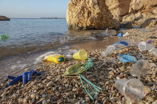 Plastic debris and face masks on the beach. Coronavirus COVID 19 is contributing to pollution, as discarded used masks clutter polluting beaches along with plastic trash. Red Sea, Sharm el Sheikh, Egypt