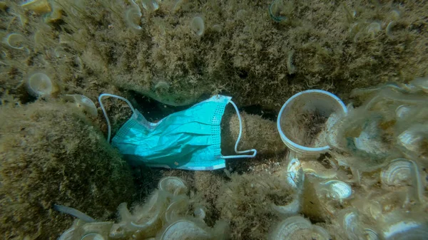 Plastic pollution - Bottles, bags and other plastic debris on seabed. Coronavirus COVID-19 is contributing to pollution, as discarded used masks clutter polluting sea bottom along with plastic trash