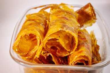 Altın sarısı yakın plan, parlak, çiğnenmiş dokusunu ve kurumuş katmanlarını gösteren cam bir kabın içinde saklanmış ayva meyvesi derisi..