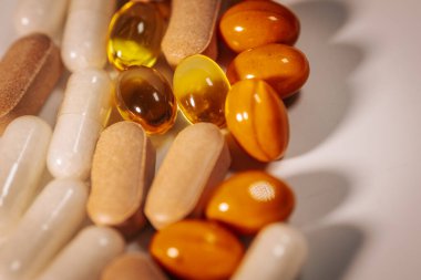 Vitamin kapsülleri ve besin takviyesi tabletlerinin bir çeşidi, merkezi metin alanı olan beyaz bir arkaplanda daire şeklinde düzenlenmiştir..