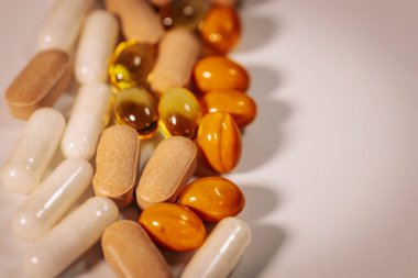 Vitamin kapsülleri ve besin takviyesi tabletlerinin bir çeşidi, merkezi metin alanı olan beyaz bir arkaplanda daire şeklinde düzenlenmiştir..