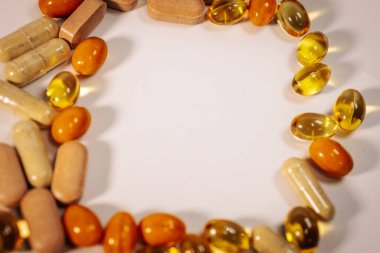 Vitamin kapsülleri ve besin takviyesi tabletlerinin bir çeşidi, merkezi metin alanı olan beyaz bir arkaplanda daire şeklinde düzenlenmiştir..