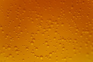 Aşırı yakın plan sarı-turuncu karbonatlı sıvı yükselen kabarcıklar desenli ve parlak bir arkaplan oluşturur.