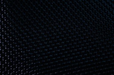 İnce gölgeler ve gölgelerle örülmüş koyu renkli bir tekstilin makro görüntüsü, ince, ızgara benzeri bir dokuyu vurguluyor. En düşük ışıklandırma.