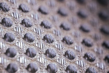 Tekrar eden dairesel dokuma deseni ve görünür iç lifleri olan solunabilir ağ kumaşının yakın plan görüntüsü..