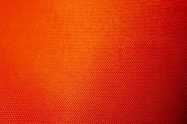 Kafes desenli ve yumuşak ışıklandırmalı turuncu sentetik kumaşın makro görüntüsü. Arkaplan olarak kullanmak için ideal.