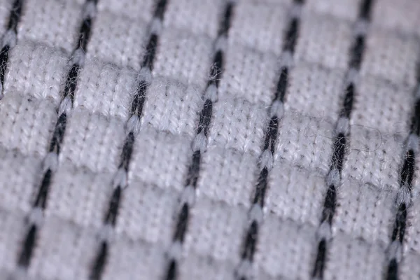 Siyah kareli şebeke desenli beyaz dokuma kumaş ve görünür tekstil lifleri. Yumuşak ışıklandırma.