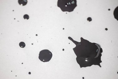 Bir siyah mürekkep koleksiyonu, temiz ve beyaz bir arkaplana yayılarak belirgin bir soyut desen oluşturur..