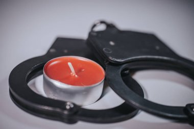 Biri kırmızı diğeri pembe olmak üzere iki aydınlatma ışığı pürüzsüz bir yüzeyde siyah metal kelepçe halkalarına yerleştiriliyor. Sıcaklık ve sınırlama temalarını birleştiren kavramsal bir resim.