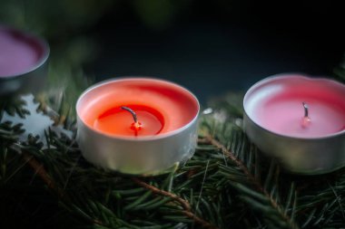 Ahşap bir mankenin elinde her zaman yeşil dallardan oluşan neşeli bir çelenk ve arka planda mumlar bulunan turuncu bir gece lambası bulunur. Samimi ve neşeli bir ruh hali..