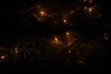 Karanlık bir arka plan karşısında sıcak, altın renkli Bokeh ışıklarının soyut bir görüntüsü, yumuşak, rüya gibi bir ışıltı yaratır..