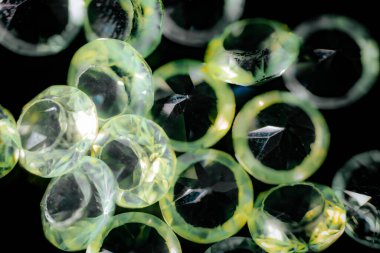 Şeffaf açık yeşil makro resim, yansıtıcı röfleler ve koyu arkaplan kontrast ile yüzleştirilmiş değerli taşlar.