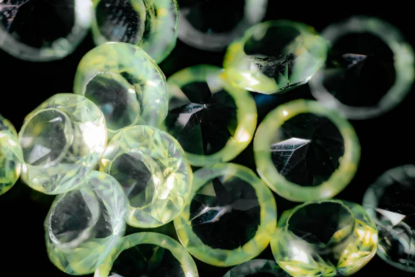 Şeffaf açık yeşil makro resim, yansıtıcı röfleler ve koyu arkaplan kontrast ile yüzleştirilmiş değerli taşlar.