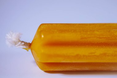 Sarı flüt mumunun makro görüntüsü ve hafif kıvrımlı beyaz brülör yumuşak mavi eğimli arka planda görünür balmumu dokusuyla.