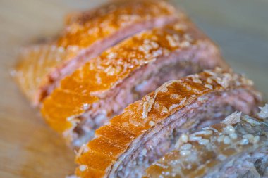 Dilimlenmiş domuz göbeği, ahşap kesme tahtasındaki çıtır çıtır deriyi ve taze eti gözler önüne seriyor. Sunumda yağ ve et katmanlarını vurguluyor.