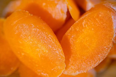 Dilimlenmiş turuncu havuçların yakın plan çekimleri pürüzsüz dokularını ve parlak renklerini vurguluyor, yumuşak odaklı arka plan görsel çekiciliği artırıyor.