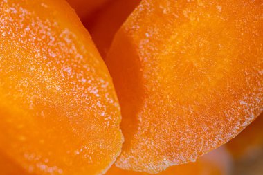 Kurumuş kayısı dilimlerinin yakın çekimlerinde parlak turuncu bir renk ve dokulu bir yüzey sergiliyorlar. Doğal tatlılıklarını ve canlı renklerini vurguluyorlar.