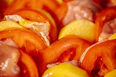 Dilimlenmiş kırmızı ve sarı dolmalık biberli, az baharatlı ve kızartılmaya hazır çiğ tavuk parçaları. Parlak renkler ve taze malzemeler yemek pişirmeyi ön plana çıkarıyor.