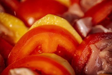 Dilimlenmiş kırmızı ve sarı dolmalık biberli, az baharatlı ve kızartılmaya hazır çiğ tavuk parçaları. Parlak renkler ve taze malzemeler yemek pişirmeyi ön plana çıkarıyor.