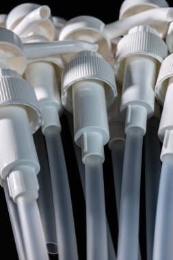 Koyu bir yüzeye yakın konumda yerleştirilmiş beyaz plastik pompa dağıtıcılarının toplanması onların yapısını ve tasarım özelliklerini vurguluyor