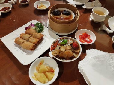 Bangkok 'ta bir Çin restoranında bambu buharlı tencerelerde servis edilen çeşitli Çin yemekleriyle dolu bir yemek masası..