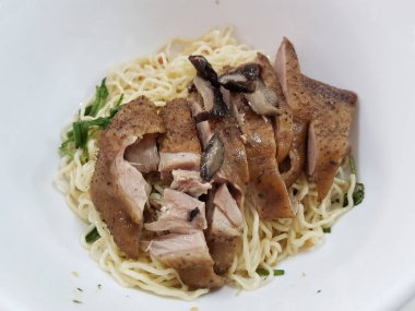 Dry-style egg noodles topped with sliced roasted duck, a classic Chinese noodle dish.