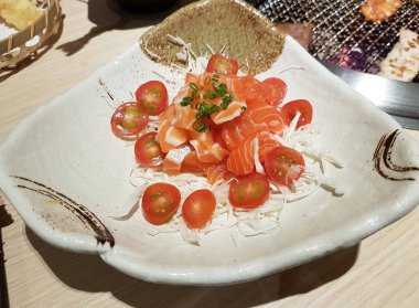 Fresh diced salmon sashimi served on shredded cabbage and halved cherry tomatoes.