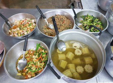 A variety of Thai dishes displayed in large pots and bowls at a local food stall in Bangkok.