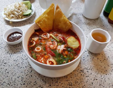 Thai-style spicy and creamy tom yum noodle soup with shrimp and squid.