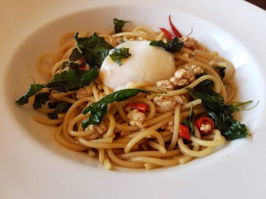 Tayland-İtalya karışımı bir yemek spagetti ile baharatlı kutsal fesleğen kıymalı domuz eti, üstüne de yumuşak onsen yumurtası..