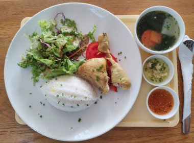 Haşlanmış pilav, haşlanmış tavuk, taze salata, sos ve sıcak bir çorba içeren düzenli bir yemek takımı..