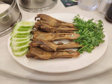 Çin usulü haşlanmış ördek gagası aromatik beş baharatlı çorba, dilimlenmiş salatalık ve kişniş ile servis edilir..