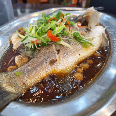 Üzeri soğanlı buğulanmış levrek, kırmızı biber ve doğranmış zencefil. Hafif soya sosuyla servis ediliyor..