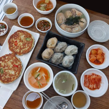 Geleneksel Kore yemekleriyle dolu bir masa. İçinde Gaeseong usulü hamur tatlısı, Kore gözlemesi ve çeşitli kimchi yemekleri var..