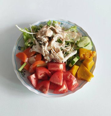 Balkabağı, salatalık, domates ve havuçla servis edilen ev yapımı tavuk göğsü salatası evde hazırlanmış sağlıklı ve besleyici bir yemek..