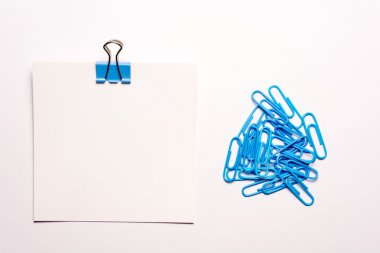 Beyaz not kağıdı ve beyaz zemin üzerine mavi ataç