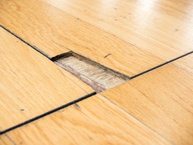 Bir arenada parke spor zemininin büyük parçalı bir bölümünün detaylı bir görüntüsü.