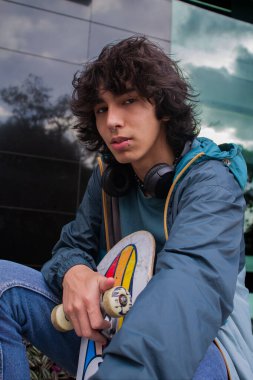Kulaklıklı ve kaykaylı kendinden emin bir genç.
