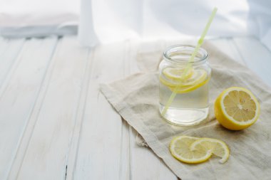 tazelik kavramı, beyaz bir yaz ahşap copyspace arka planda bir kavanozda limon dilimleri ile Limonata