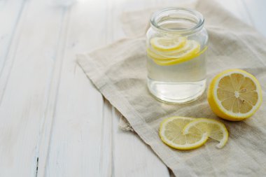 tazelik kavramı, beyaz bir yaz ahşap copyspace arka planda bir kavanozda limon dilimleri ile Limonata