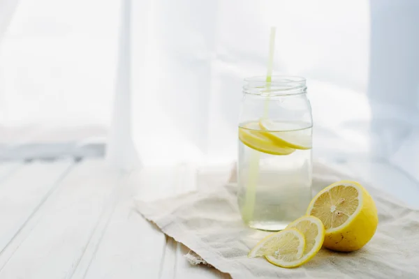 Concetto di freschezza, Limonata con fette di limone in un barattolo su uno sfondo di legno bianco estivo — Foto Stock