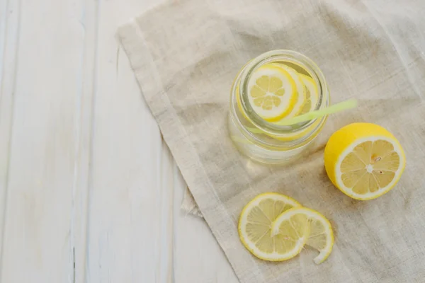 Свежесть концепции, лимонад с ломтиками лимона в банке с соломой на белом деревянном фоне — стоковое фото