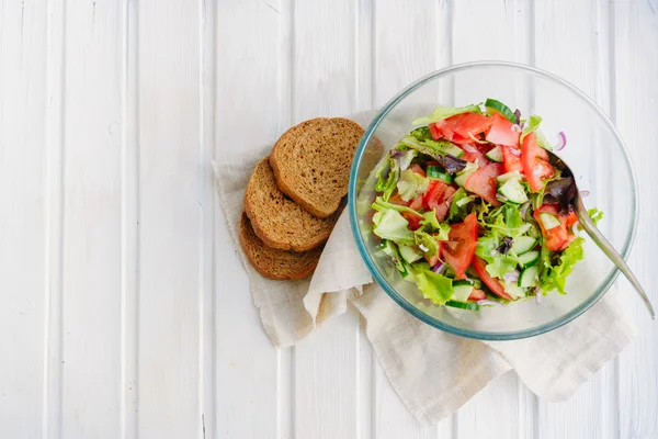 Gusto di concetto estivo vegetariano, insalata di foglia di lattuga, pomodoro, cetriolo, cipolla, origano con olio d'oliva e succo di limone su fondo di legno bianco con copyspace — Foto Stock