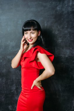 Güzel genç model kadın siyah arduvaz arka plan üzerinde poz Kırmızı elbiseli