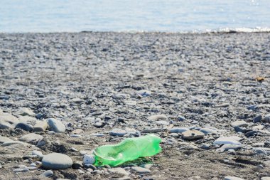 Çakıl taşlı plajda buruşmuş plastik şişe, çevre koruma konsepti, yatay yaşam tarzı fotoğraf arkaplanı